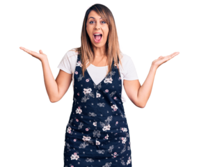 Young beautiful woman wearing casual floral dress celebrating victory with happy smile and winner expression with raised hands