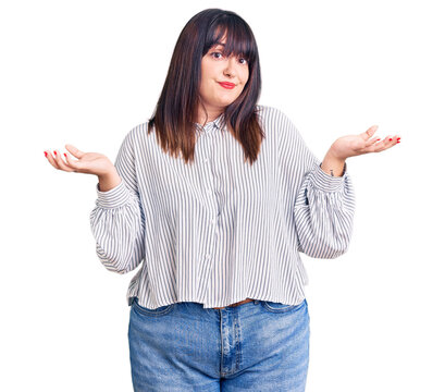 Young plus size woman wearing casual clothes clueless and confused expression with arms and hands raised. doubt concept.