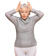 Senior grey-haired woman wearing casual winter sweater doing bunny ears gesture with hands palms looking cynical and skeptical. easter rabbit concept.