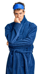 Young handsome man wearing sleep mask and bathrobe thinking looking tired and bored with depression problems with crossed arms.