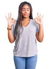 Young african american woman with braids wearing casual clothes relax and smiling with eyes closed doing meditation gesture with fingers. yoga concept.