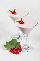 Vegan dessert. Red currant cream Panna Cotta, decorated with fresh red currant berries, in a martini glass. White background. Close up