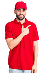 Young handsome man with beard wearing delivery uniform cheerful with a smile on face pointing with hand and finger up to the side with happy and natural expression