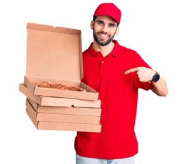 Young handsome man with beard wearing delivery uniform holding boxes with pizza pointing finger to one self smiling happy and proud
