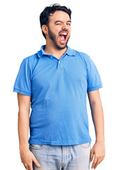 Fototapeta premium Young hispanic man wearing casual clothes winking looking at the camera with sexy expression, cheerful and happy face.