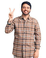 Naklejka premium Young hispanic man wearing casual clothes showing and pointing up with fingers number two while smiling confident and happy.