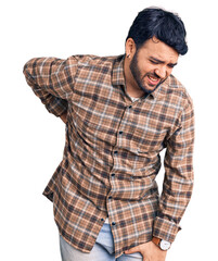 Young hispanic man wearing casual clothes suffering of backache, touching back with hand, muscular pain