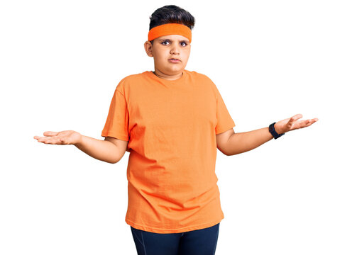 Little boy kid wearing sportswear clueless and confused with open arms, no idea concept.