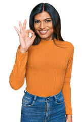 Young latin transsexual transgender woman wearing casual clothes smiling positive doing ok sign with hand and fingers. successful expression.