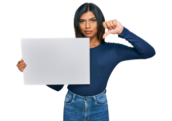 Young latin transsexual transgender woman holding blank empty banner with angry face, negative sign showing dislike with thumbs down, rejection concept