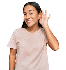 Young asian woman wearing casual clothes smiling with hand over ear listening an hearing to rumor or gossip. deafness concept.