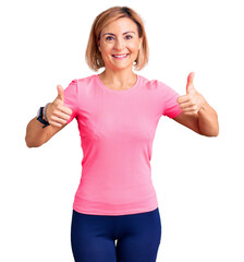 Young blonde woman wearing sportswear success sign doing positive gesture with hand, thumbs up smiling and happy. cheerful expression and winner gesture.