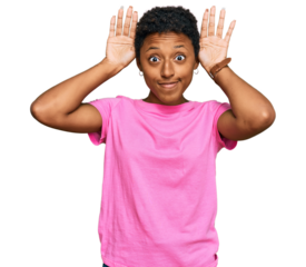 Young african american woman wearing casual clothes doing bunny ears gesture with hands palms looking cynical and skeptical. easter rabbit concept.