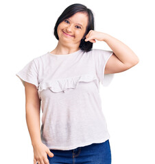 Fototapeta premium Brunette woman with down syndrome wearing casual white tshirt smiling doing phone gesture with hand and fingers like talking on the telephone. communicating concepts.