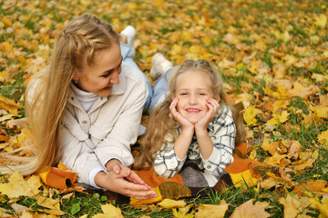 The family has fun in the park. Girl and mother lie on a blanket, the girl looks at the camera and smiles