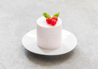 Red currant Panna Cotta cylindrical shape, on a plate. Light gray background. Close-up