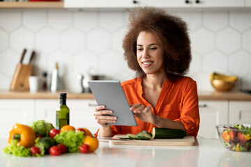 Online Recipe. Smiling african american woman using digital tablet in kitchen