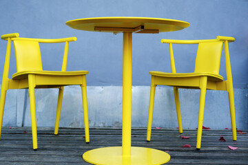 Yellow chairs and a table stand on the summer terrace of a city cafe