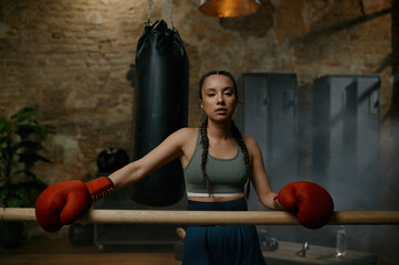 Athletic female fighter with bandaged hands standing leaned at wooden bar