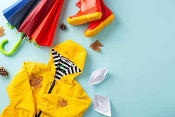 Autumn dreamscape. Top view of child's yellow raincoat, red gumshoes, colorful umbrella, paper...