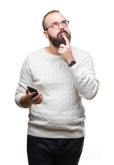 Young caucasian hipster man texting sending message using smartphone over isolated background serious face thinking about question, very confused idea