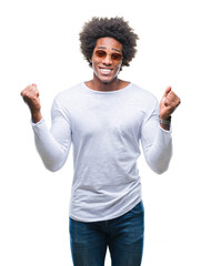 Afro american man wearing sunglasses over isolated background celebrating surprised and amazed for success with arms raised and open eyes. Winner concept.
