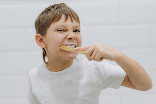 cute 8 years old boy brushing teeth with bamboo tooth brush in bathroom. Image with selective focus