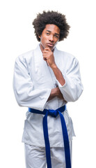 Obraz na płótnie Canvas Afro american man wearing karate kimono over isolated background looking confident at the camera with smile with crossed arms and hand raised on chin. Thinking positive.