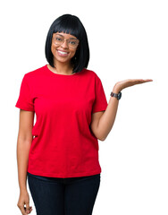Beautiful young african american woman wearing glasses over isolated background smiling cheerful presenting and pointing with palm of hand looking at the camera.