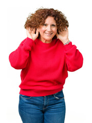 Beautiful middle ager senior woman red winter sweater over isolated background Trying to hear both hands on ear gesture, curious for gossip. Hearing problem, deaf