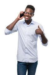 Fototapeta premium Young african american man using smartphone happy with big smile doing ok sign, thumb up with fingers, excellent sign