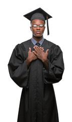 Young graduated african american man over isolated background smiling with hands on chest with closed eyes and grateful gesture on face. Health concept.