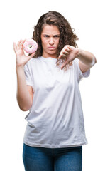 Young brunette girl eating donut over isolated background with angry face, negative sign showing...