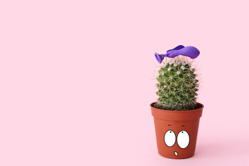 Cactus in pot with drawn shocked face and popped air balloon on pink background. Banner for design