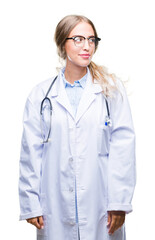 Beautiful young blonde doctor woman wearing medical uniform over isolated background smiling looking side and staring away thinking.