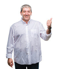 Handsome senior man over isolated background smiling with happy face looking and pointing to the side with thumb up.