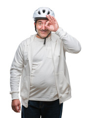 Handsome senior cyclist man wearing bike helmet over isolated background with happy face smiling doing ok sign with hand on eye looking through fingers