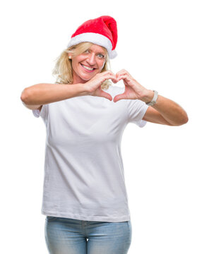 Middle age blonde woman wearing christmas hat over isolated background smiling in love showing heart symbol and shape with hands. Romantic concept.