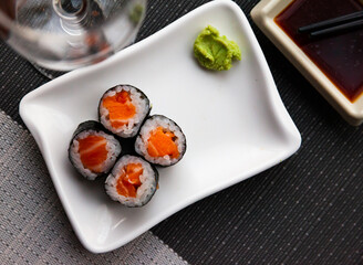 Fototapeta na wymiar Maki sushi rolls with raw salmon inside served with wasabi