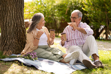 Happy senior european man and woman eat sandwiches, drink coffee takeaway, enjoy romantic date,...