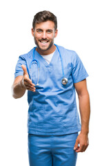 Fototapeta premium Young handsome doctor surgeon man over isolated background smiling friendly offering handshake as greeting and welcoming. Successful business.