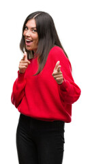 Young beautiful hispanic wearing red sweater pointing fingers to camera with happy and funny face. Good energy and vibes.
