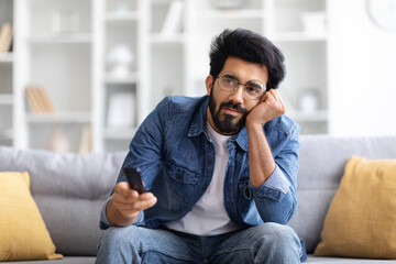 Portrait Of Bored Young Eastern Man Watching TV At Home