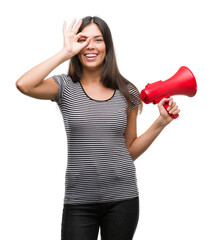 Young hispanic woman holding megaphone with happy face smiling doing ok sign with hand on eye looking through fingers