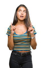 Young beautiful arab woman over isolated background amazed and surprised looking up and pointing with fingers and raised arms.