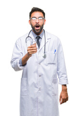 Adult hispanic doctor man drinking glass of water over isolated background scared in shock with a surprise face, afraid and excited with fear expression