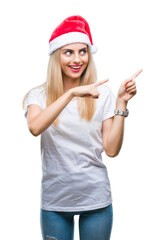 Obraz na płótnie Canvas Young beautiful blonde woman christmas hat over isolated background smiling and looking at the camera pointing with two hands and fingers to the side.