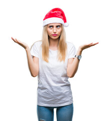 Obraz na płótnie Canvas Young beautiful blonde woman christmas hat over isolated background clueless and confused expression with arms and hands raised. Doubt concept.
