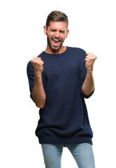 Fototapeta premium Young handsome man wearing winter sweater over isolated background very happy and excited doing winner gesture with arms raised, smiling and screaming for success. Celebration concept.