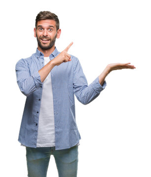 Young handsome man wearing white t-shirt over isolated background amazed and smiling to the camera while presenting with hand and pointing with finger.